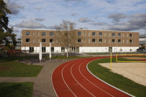 Schulwohnheim mit gegenüber liegenden Sportplatz im Vordergrund